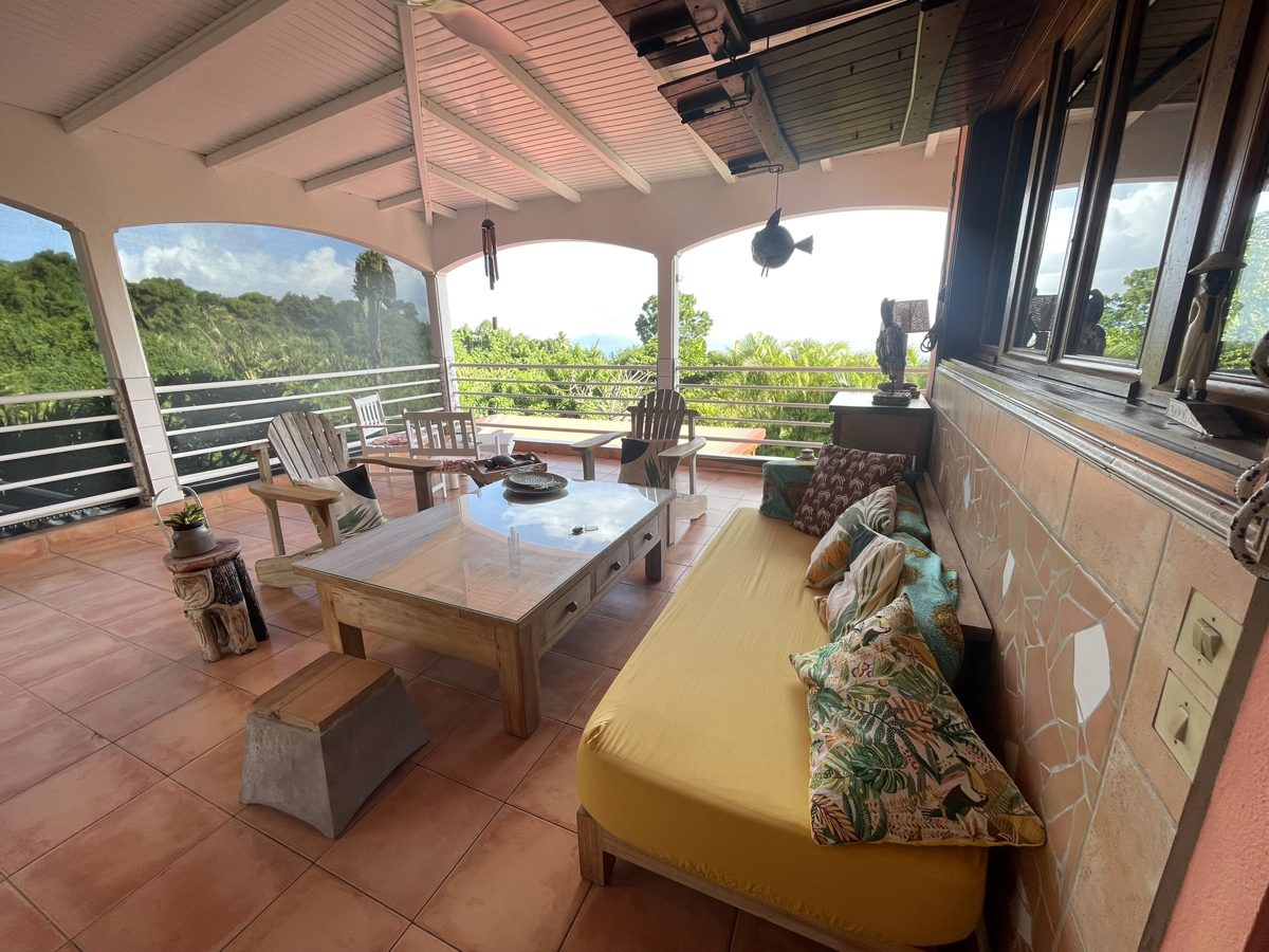 Terrasse créole avec banquette jaune et vue sur la végétation
